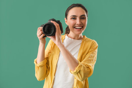 Female photographer with professional camera on green backgroundの写真素材