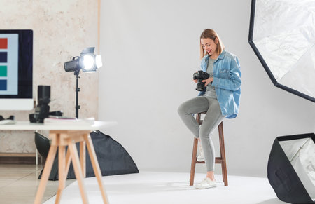 Female photographer with professional camera sitting in studioの写真素材