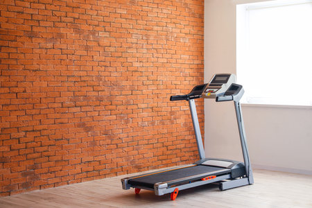 Interior of room with modern treadmill near brick wallの写真素材