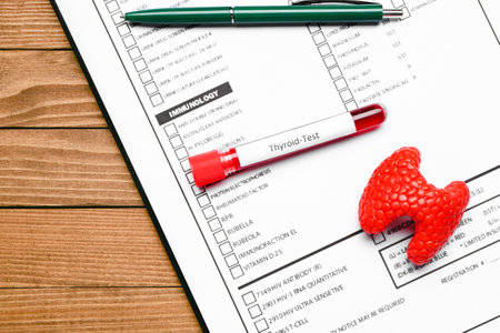Blood sample in tube with model of thyroid and laboratory test form on wooden backgroundの写真素材