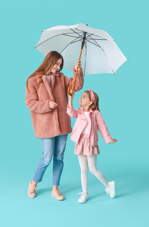 Mother and little daughter with umbrella on color backgroundの写真素材