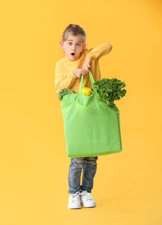 Surprised little girl with food in bag on color backgroundの写真素材