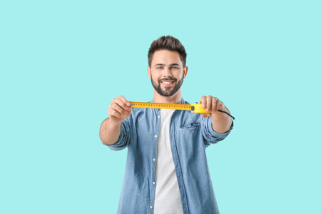 Young man with measuring tape on color backgroundの写真素材