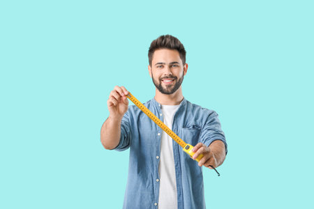 Young man with measuring tape on color backgroundの写真素材