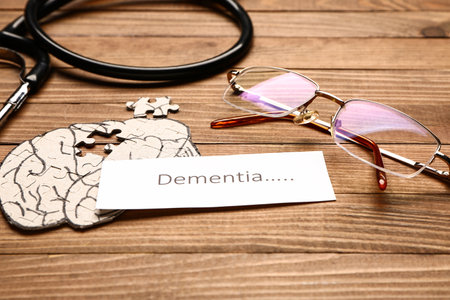 Word DEMENTIA with human brain, eyeglasses and stethoscope on wooden backgroundの写真素材