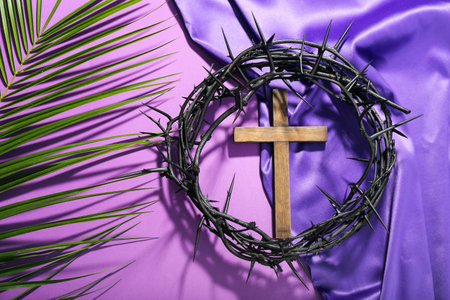 Wooden cross with crown of thorns, palm leaf and purple fabric on violet background. good friday conceptの写真素材
