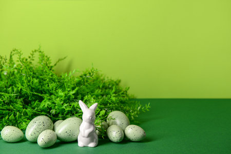 Easter eggs, porcelain bunny and plant leaves on green backgroundの写真素材