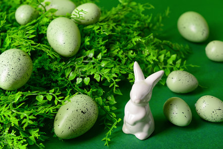 Easter eggs, porcelain bunny and plant leaves on green backgroundの写真素材