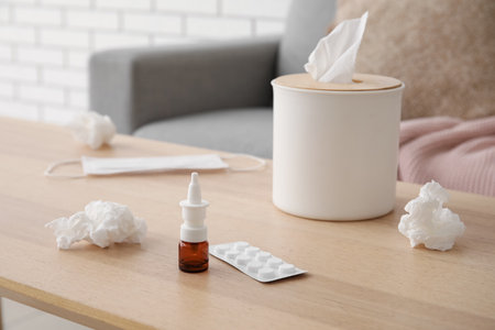 Nasal drops with pills and tissue box on table in living room, closeup. Allergy conceptの写真素材