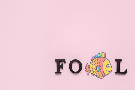 Word FOOL with paper fish on pink backgroundの写真素材
