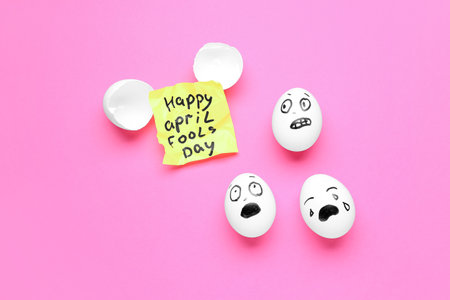 Paper with text HAPPY APRIL FOOLS DAY and eggs on pink backgroundの写真素材