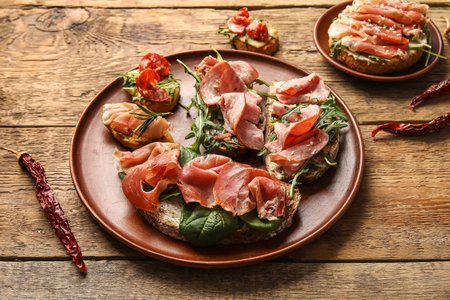 Plates of tasty bruschettas with ham on wooden backgroundの写真素材