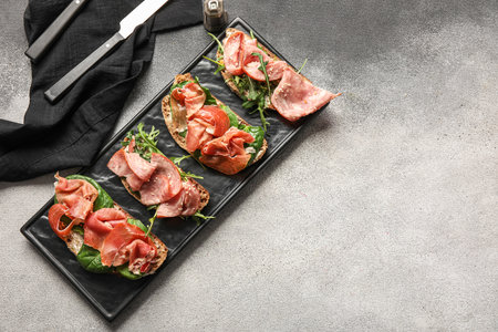 Board of tasty bruschettas with ham on grunge backgroundの写真素材