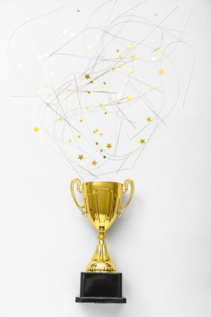 Gold cup with confetti on light backgroundの写真素材