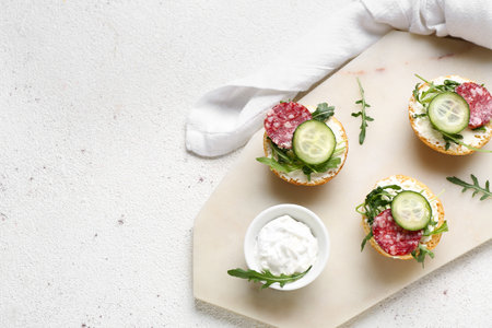 Board with delicious sandwiches and cream cheese on light backgroundの写真素材