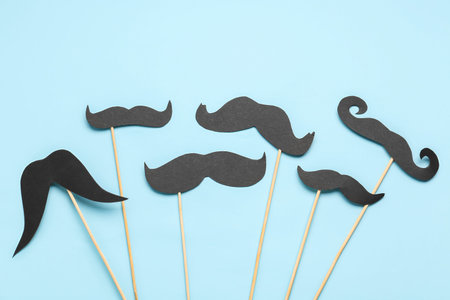 Set of different paper mustaches on sticks against color background