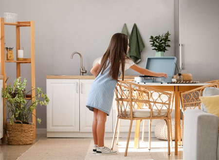 Little girl with record player on table in kitchenの写真素材