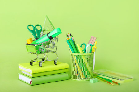 Shopping cart with stationery on green backgroundの写真素材
