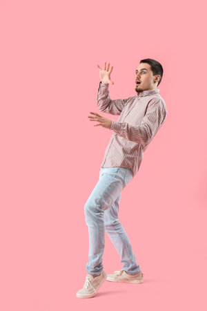 Scared young man on pink backgroundの写真素材