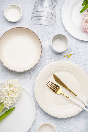 Composition with clean dishes, cutlery and beautiful flowers on gray grunge backgroundの写真素材