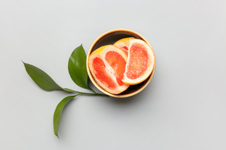 Bowl with pieces of ripe grapefruit and plant branch on light backgroundの写真素材