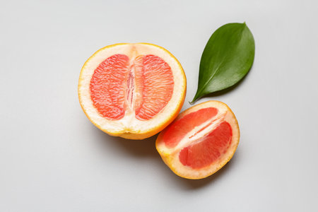 Pieces of ripe grapefruit and plant leaf on light backgroundの写真素材