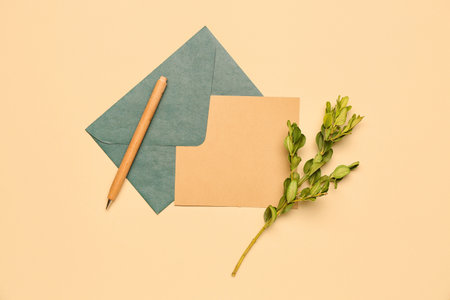 Composition with blank card, envelope, pen and plant branch on color backgroundの写真素材