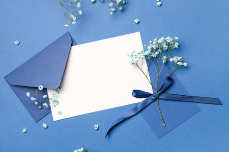Composition with blank card, envelope and beautiful gypsophila flowers on blue backgroundの写真素材