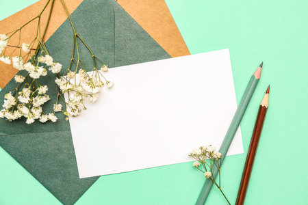Composition with blank card, envelopes, pencils and gypsophila flowers on color background, closeupの写真素材