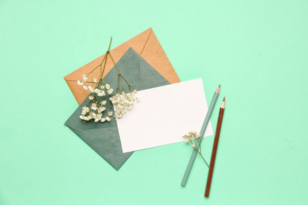 Composition with blank card, envelopes, pencils and gypsophila flowers on color background