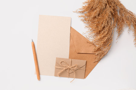 Composition with blank card, envelopes, pen and pampas grass on white backgroundの写真素材