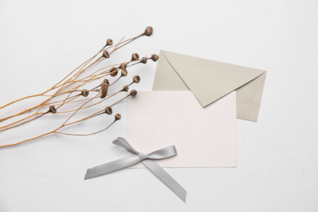 Composition with blank card, envelope and dried flowers on white backgroundの写真素材