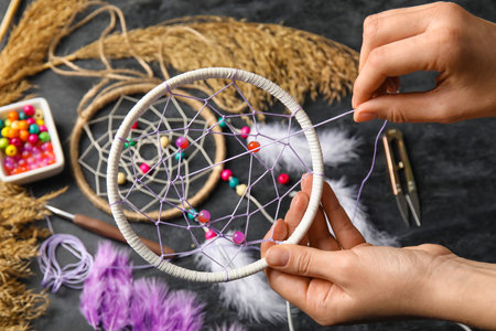 Woman making dream catcher on dark table, closeupの写真素材