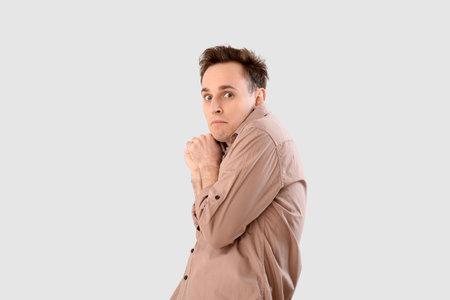 Scared young man on light background