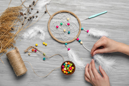 Woman making dream catcher on gray wooden backgroundの写真素材