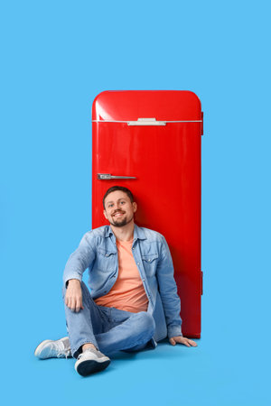 Handsome man with big blank poster sitting on blue backgroundの写真素材