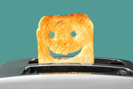 Funny slice of bread in modern toaster on green background