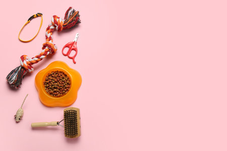 Pet care accessories and bowl of dry food on pink backgroundの写真素材