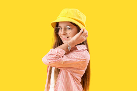 Little girl with wrist watch on yellow backgroundの写真素材
