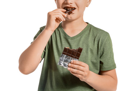 Cute little boy eating chocolate on white backgroundの写真素材
