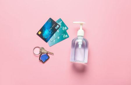Credit cards with key from house and disinfectant on color background