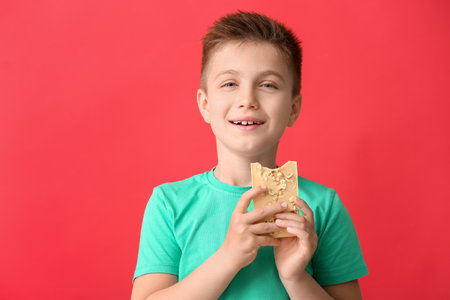 Cute little boy with chocolate on color backgroundの写真素材
