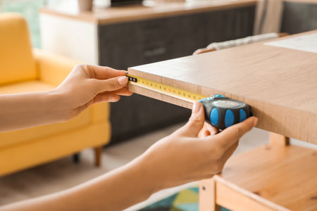 Young woman taking measures of table in kitchen, closeupの写真素材