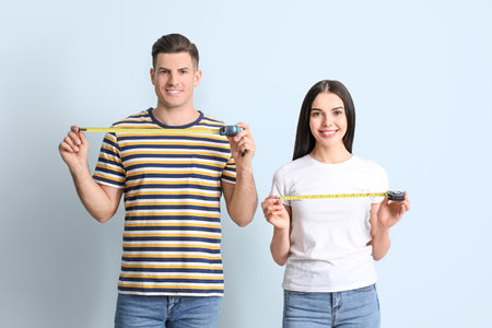 couple with measuring tapes on color backgroundの写真素材
