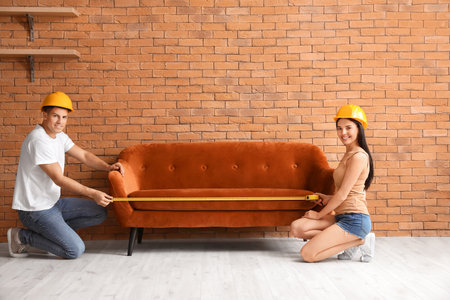 Couple with measuring tape near sofa in roomの写真素材