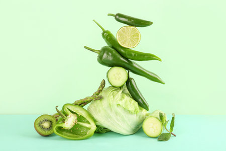 Composition with different fresh green vegetables on color background