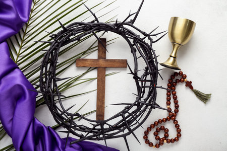Wooden cross with crown of thorns, prayer beads, wine cup and palm leaf on white background. good...
