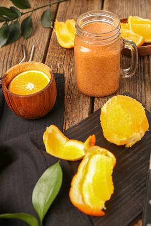 Glass of healthy smoothie and peeled orange on wooden tableの写真素材