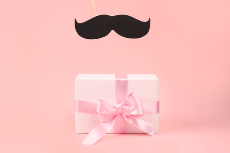 Gift box with paper mustache on pink backgroundの写真素材