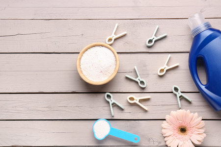 Laundry detergents, clothespins and gerbera flower on wooden background